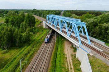 Pociąg jadący pod wiaduktem kolejowym. Autor Przemysław Arabski